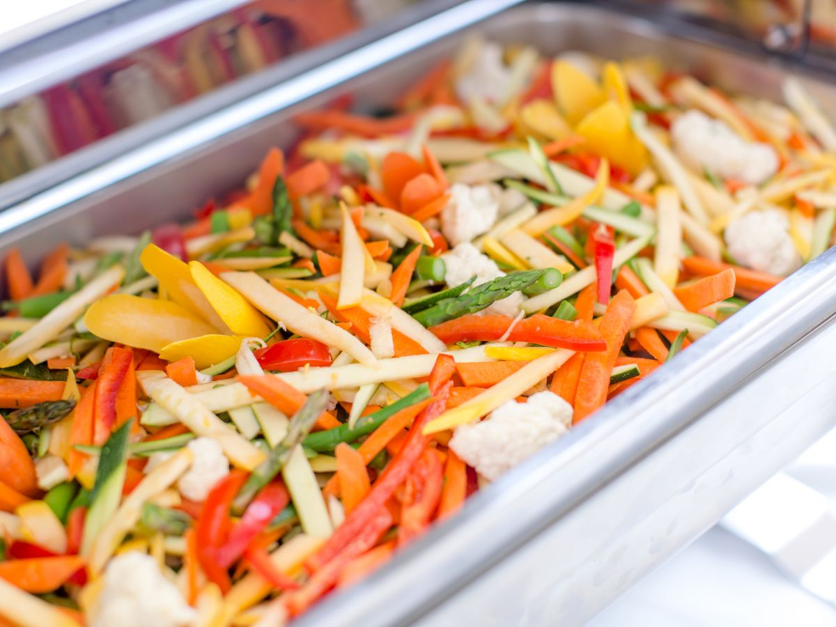 The image shows a tray filled with a colorful assortment of mixed vegetables, including carrots, bell peppers, asparagus, and cauliflower.